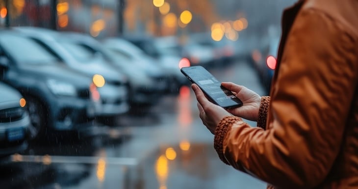 Professionnel consultant son téléphone devant une concession automobile