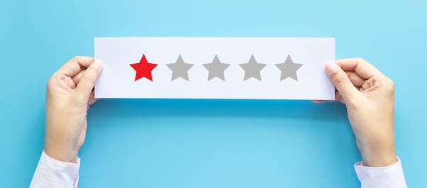 2 mains tiennent une feuille avec une seule étoile rouge sur 5, cela illustre un avis client négatif