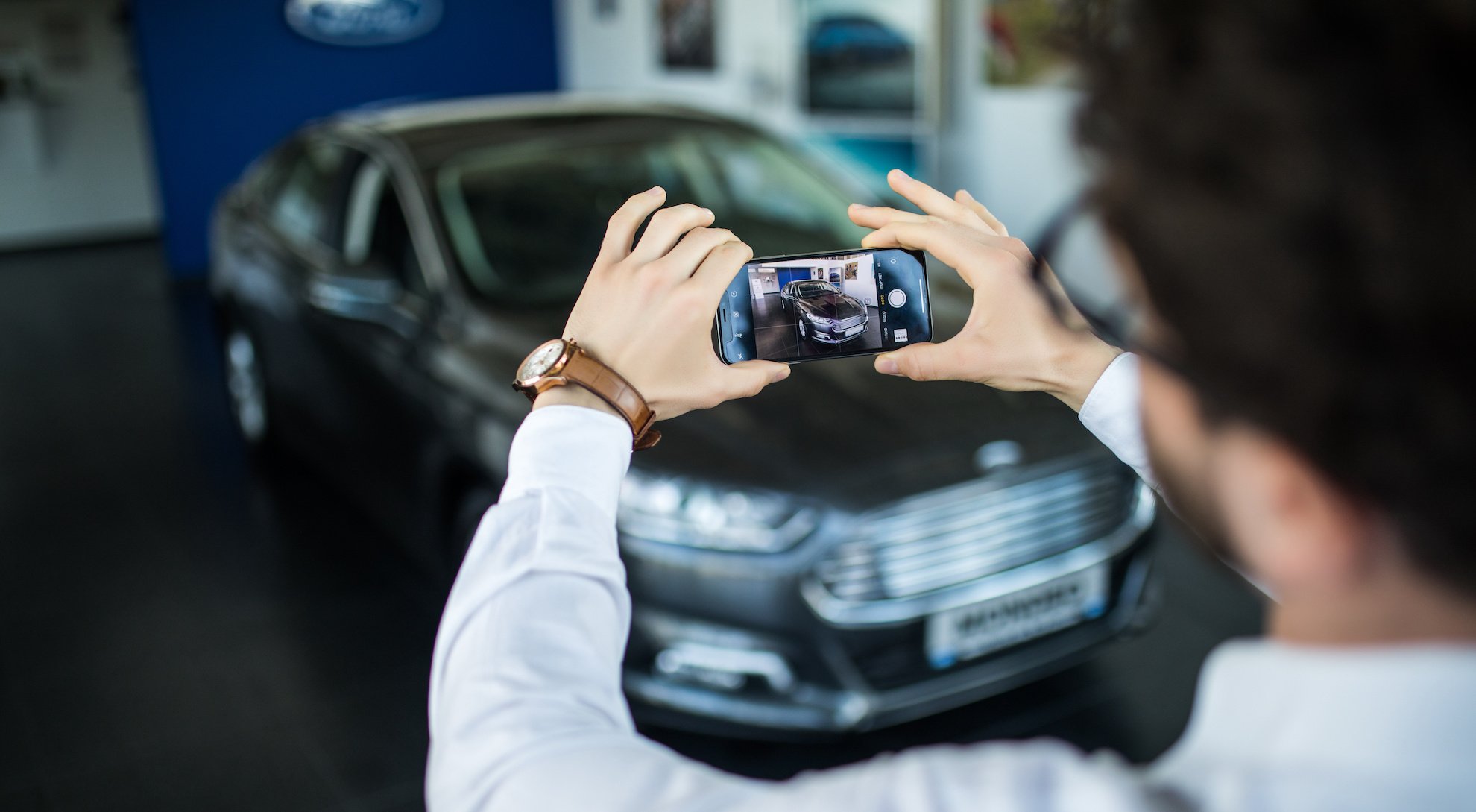 Un homme qui prend une voiture en photo avec son smartphone